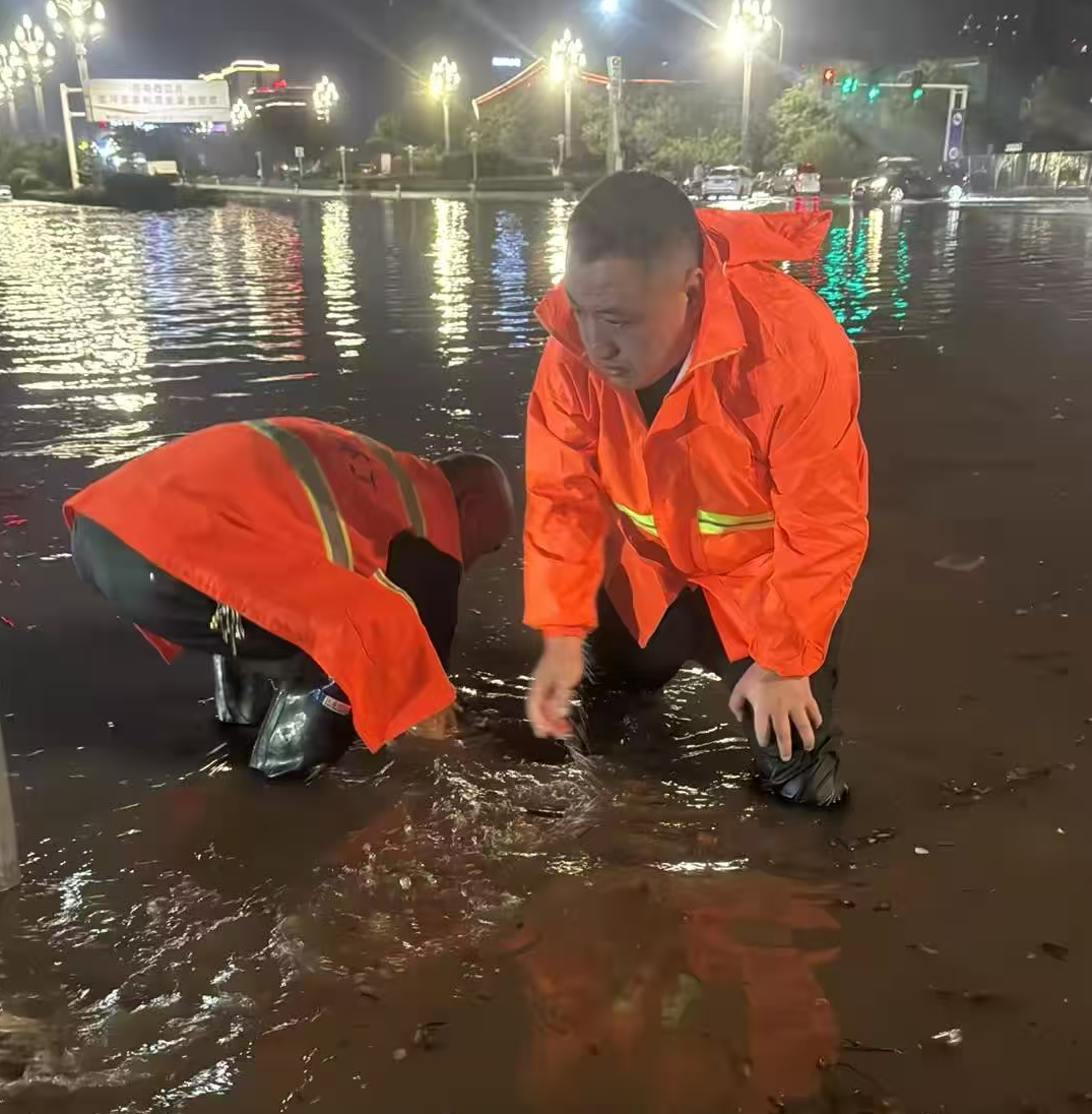 神州環境副總經理孔凡超帶領環衛團隊在雨中疏通下水道口.png